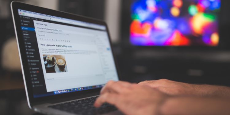 man writing blog content in WordPress on a laptop