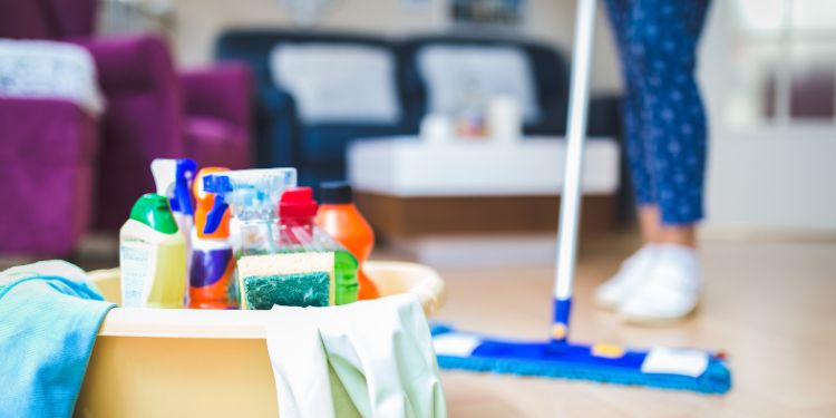 cleaning products on display with woman cleaning in the background