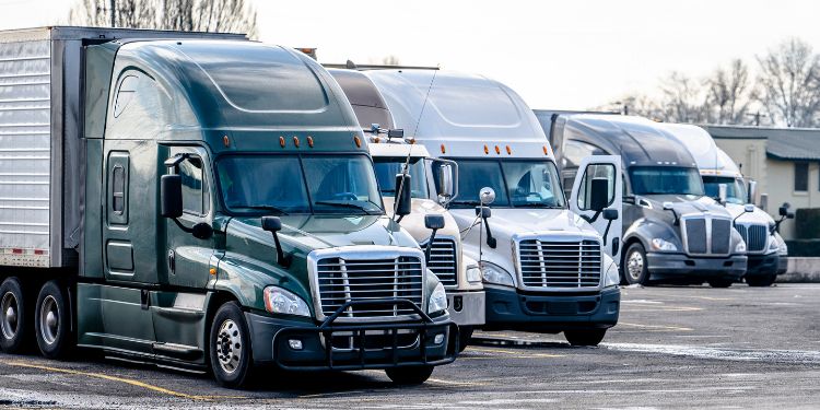 4 commercial trucks parked on the pavement