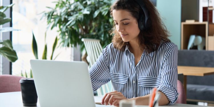 Woman typing at a customer service job with headphones