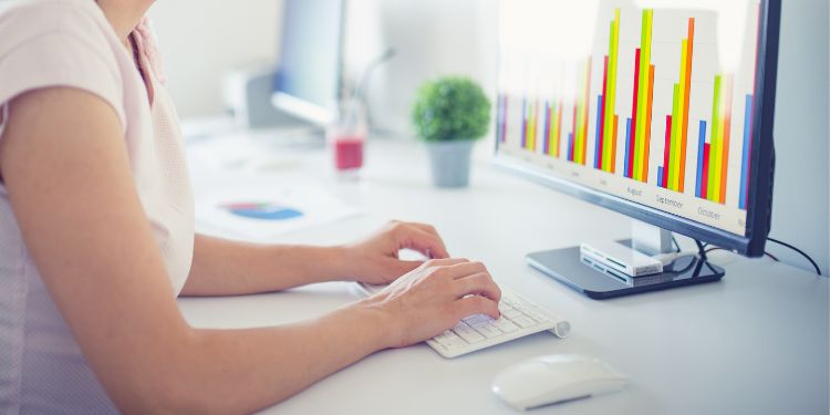 Woman entering data from a graph on a computer