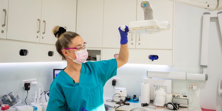 Dental hygienist holding a light in a dentist office