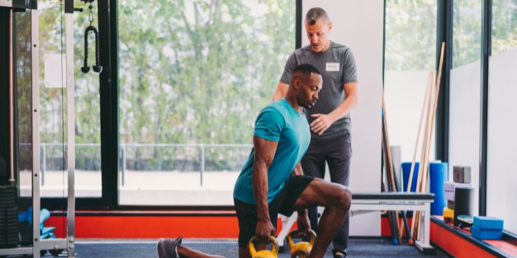 personal trainer helping a man workout